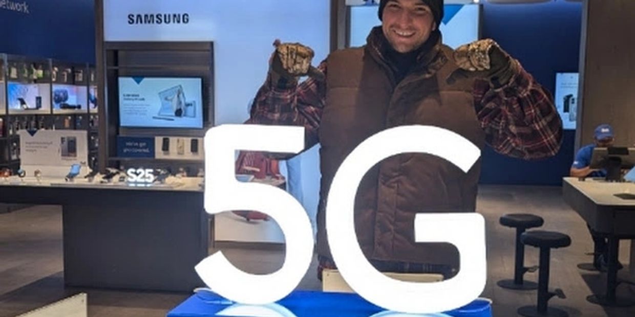 Man posing with illuminated 5G sign in Samsung store.