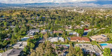 Aerial view of a suburban neighborhood with greenery and mountains in the background.