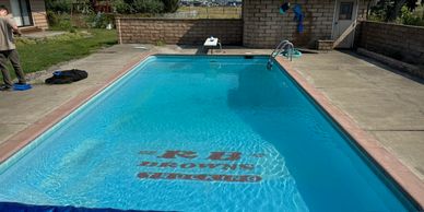 A clear outdoor swimming pool with a 'No Diving' sign at the bottom.