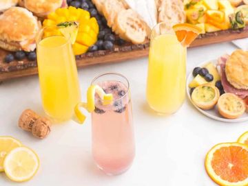 Three colorful cocktails with fruits on a white table.