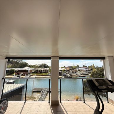 Covered balcony overlooking water and houses with treadmill.