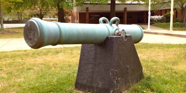 Antique cannon mounted on a stone base outdoors.