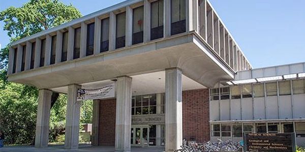 A modern academic building with pillars and bicycles parked outside.