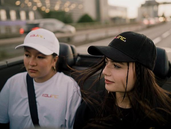 two girls wearing black and white caps and driving a car