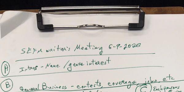 Handwritten notes on a clipboard about a writer's meeting agenda dated 6-9-2020.