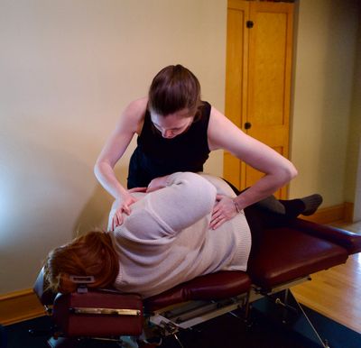 A chiropractor adjusts a patient's back on a treatment table.