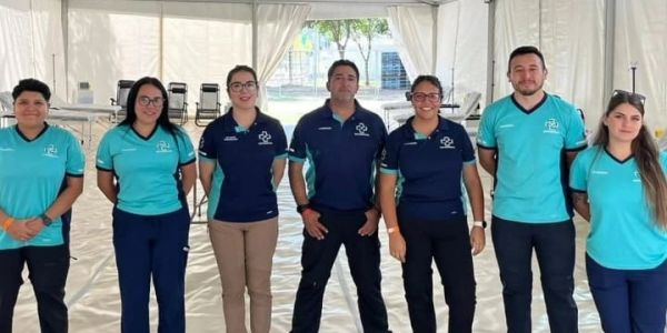 Group photo of seven people in matching uniforms outdoors.