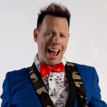 Rock and roll musician and singer in blue tuxedo and red bow tie with camouflage guitar strap