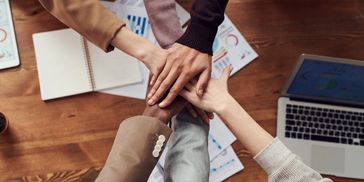 Persone che uniscono le mani su una scrivania.