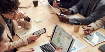 Persone che collaborano usando dispositivi digitali durante una riunione.