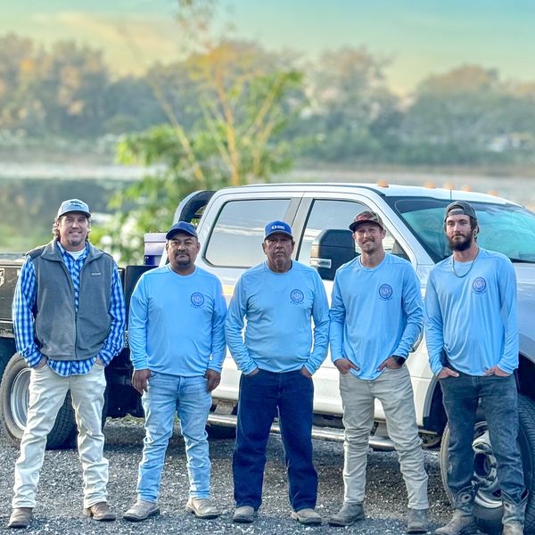 Five men standing in front of a white truck outdoors.