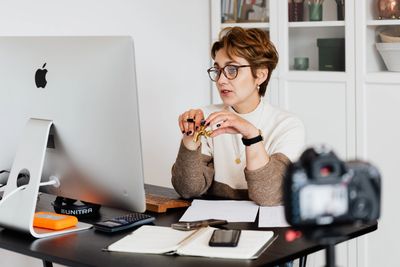 Female executive with short red hair sitting in front of an I-mac. 