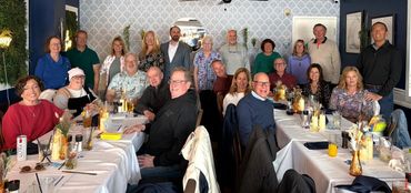 A group of people gathered around tables in a restaurant for a celebration.