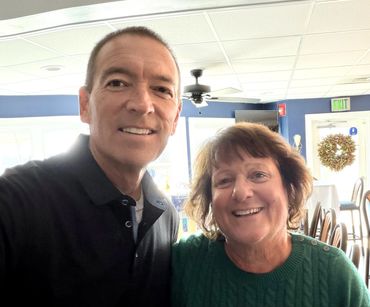 A man and woman smiling indoors in a bright room.