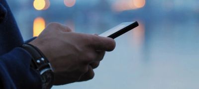 Person using a smartphone with blurred background lights.