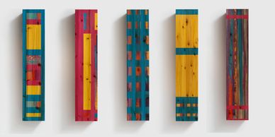 Colorful vertical wooden panels with geometric patterns mounted on a wall.