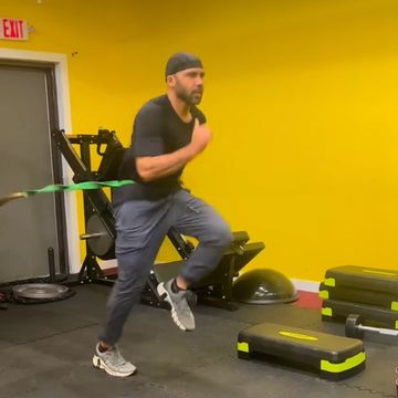 Man exercising with resistance band in a gym.