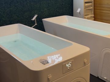 Two modern bathtubs filled with water in a clean bathroom.