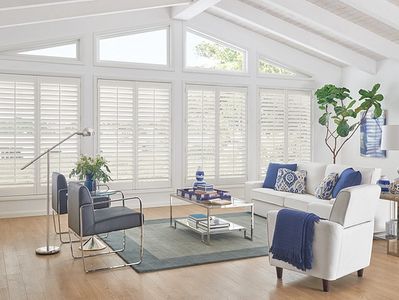 Bright living room with white and blue furniture and large windows.