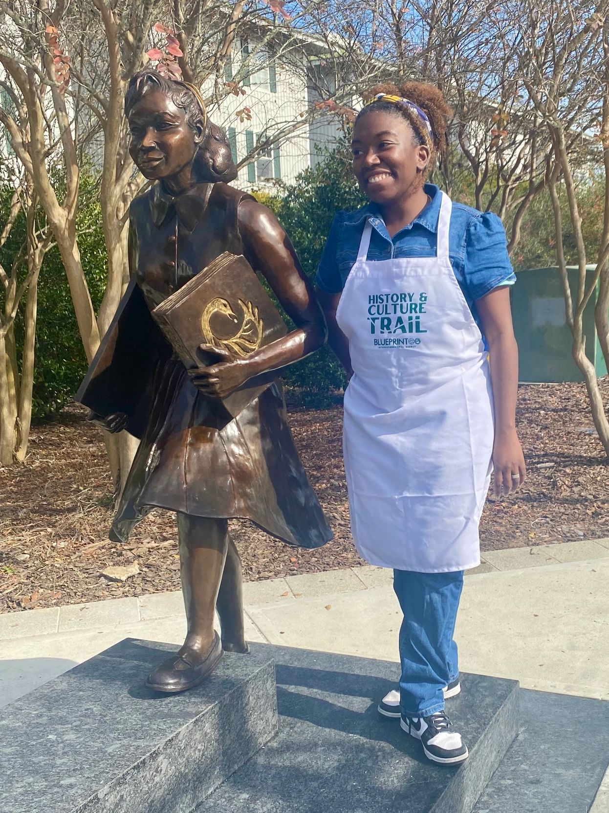 Bronze statue of student holding a book. African American, woman artist standing on steps