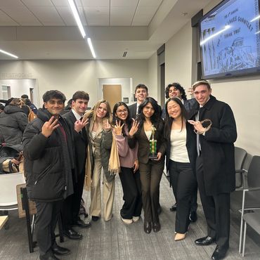 Group of young professionals posing together indoors, some holding awards.