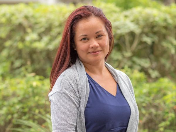 Smiling woman with red hair outdoors in casual attire.