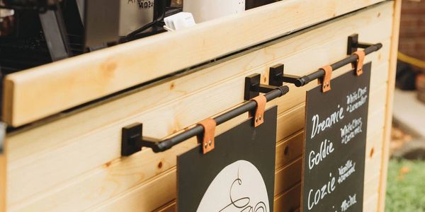 A cozy outdoor coffee stand with a wooden counter and handwritten menu.