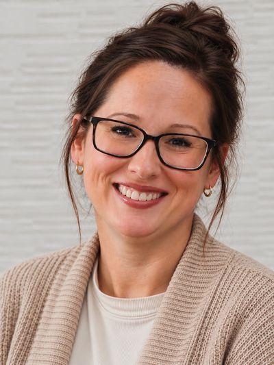 Smiling woman with glasses and casual clothing.