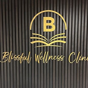 Elegant gold logo and text for Blissful Wellness Clinic on dark striped wall.