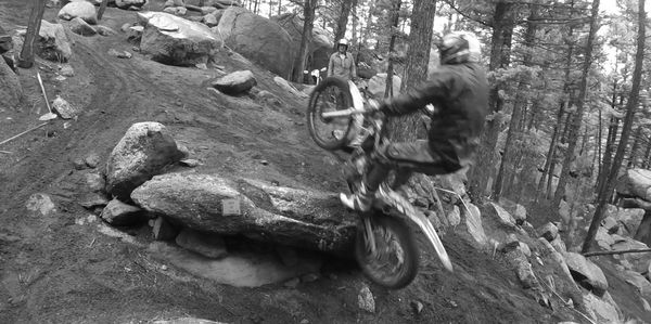 A master level rider overcoming an undercut boulder on a wet day. 