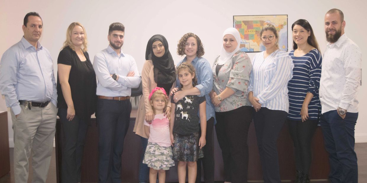 Group photo of Leena Trucking staff, men and women and two of their children. 