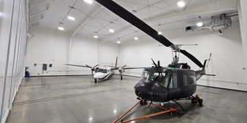 Inside a spacious hangar with a helicopter and a small airplane parked.