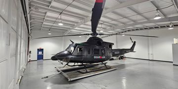 A black Coast Guard helicopter inside a spacious hangar.