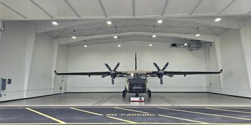 Twin-engine aircraft parked inside a spacious hangar.