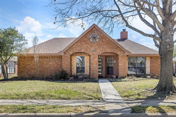 Single-story brick house with a front yard and a large tree.