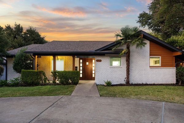 Single-story house with white brick and wooden accents at sunset.