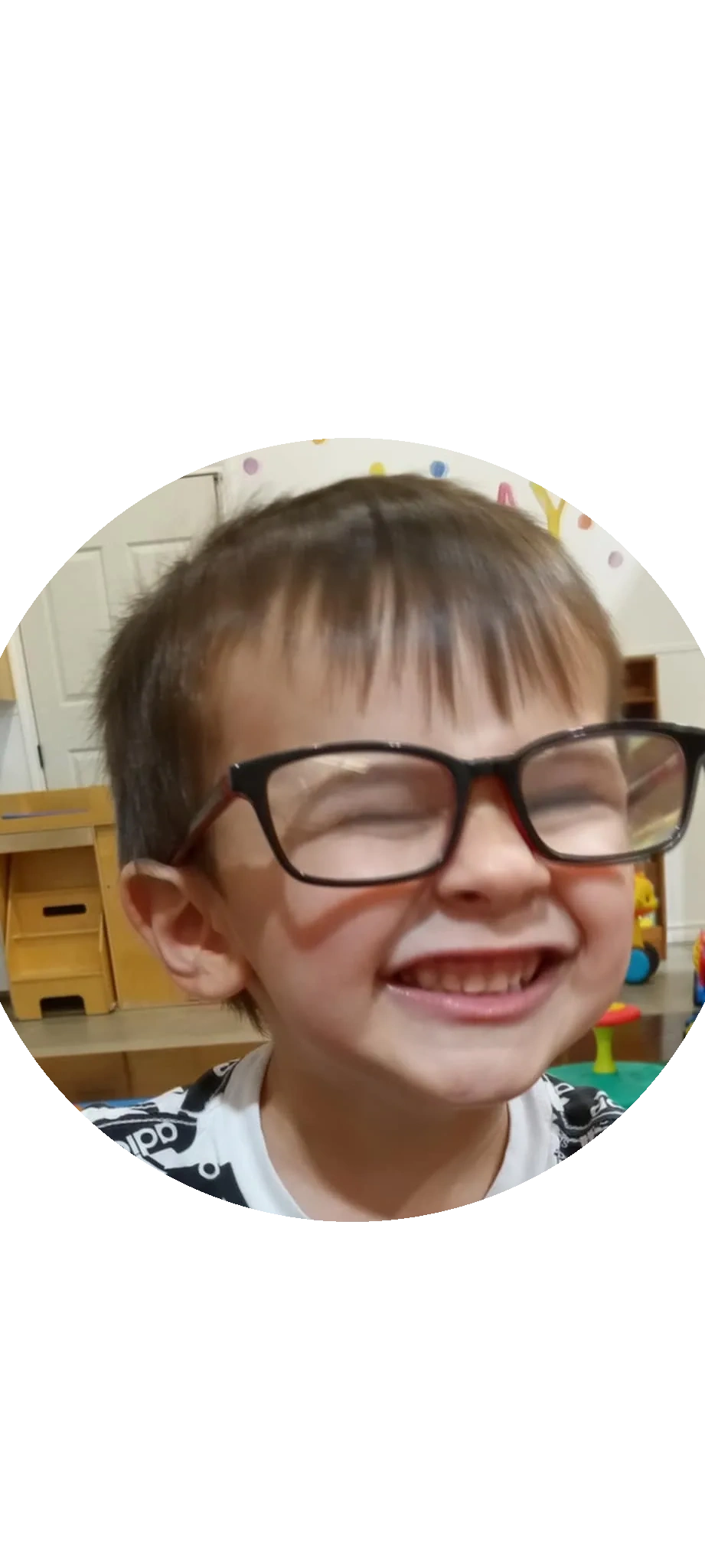 Happy child laughing with oversized glasses indoors.
