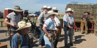 Group of men in cowboy hats preparing for a shooting event outdoors.
