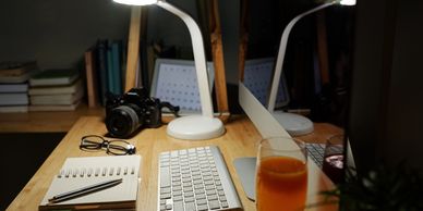 home work station with desk lamp illuminating keyboard and notebook. 