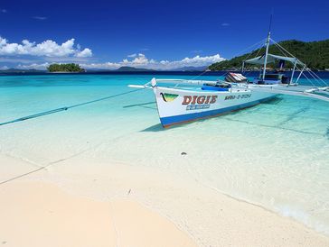 Traditional Philippines boat in Dinagat Islands on a pristine white sand beach with turquoise water