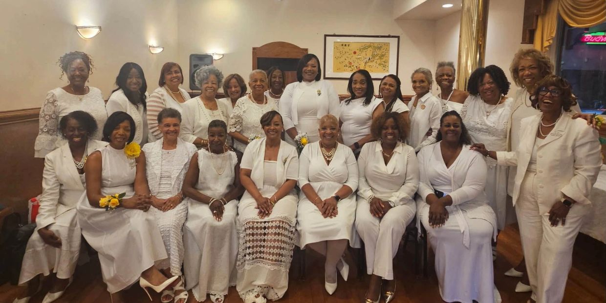 Group of women dressed in white posing indoors.
