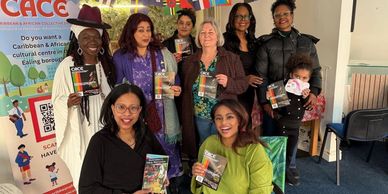 Group of diverse women smiling and holding cultural brochures indoors.