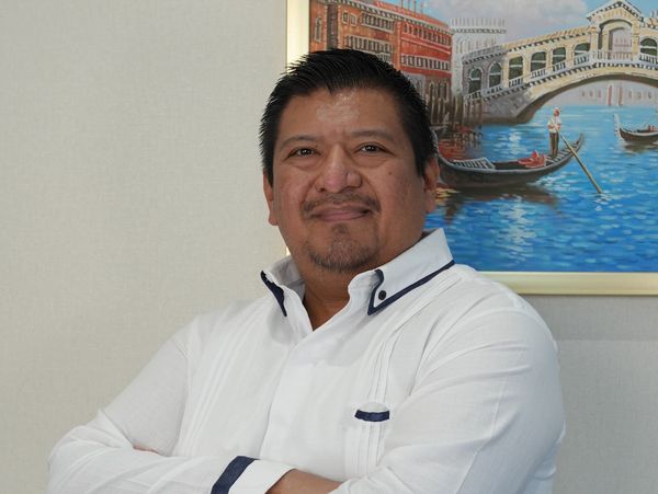 Man in white shirt posing confidently with folded arms indoors.