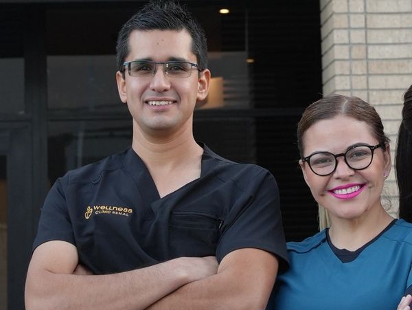 Two smiling healthcare professionals in scrubs and glasses.