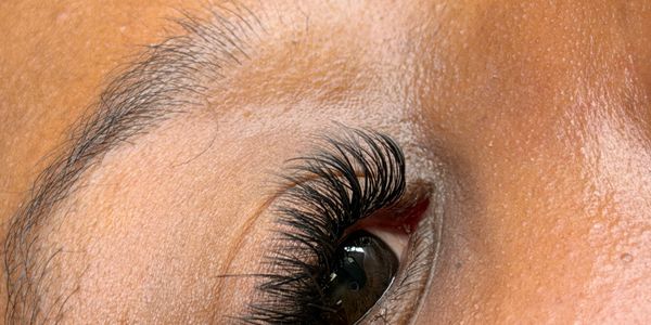 Close-up of an eye with long, thick eyelashes and smooth skin.