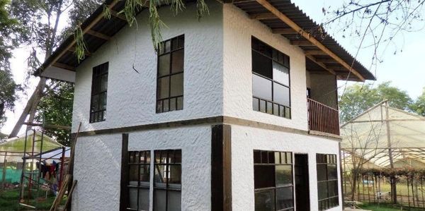 Two-story white house with black window frames and a sloped roof.