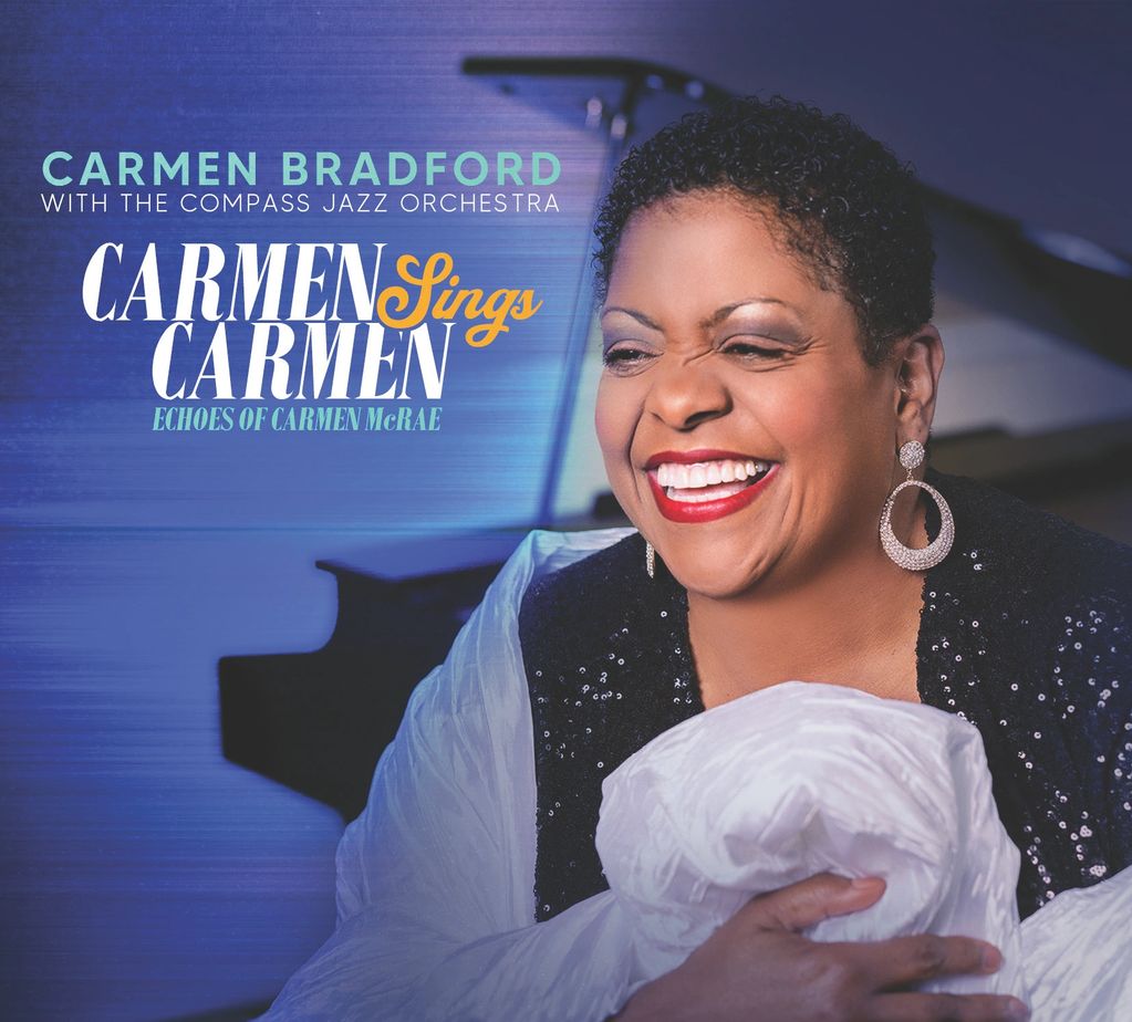 Carmen Bradford joyfully smiling with a piano in the background.