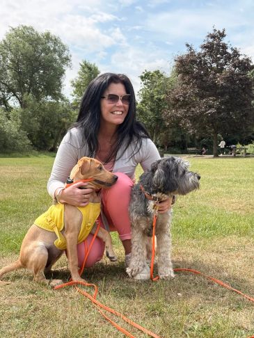 Woman with two dogs in a park on a sunny day.