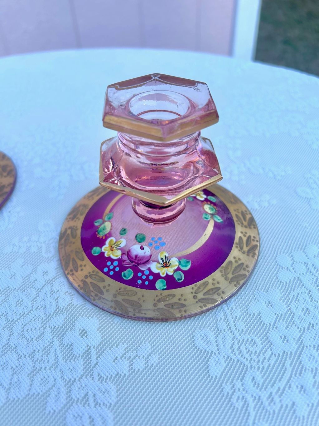 up close of hand painted pink vintage candle holders displayed on white lace linen