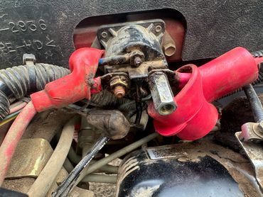 Close-up of a vehicle starter relay with red cables.
